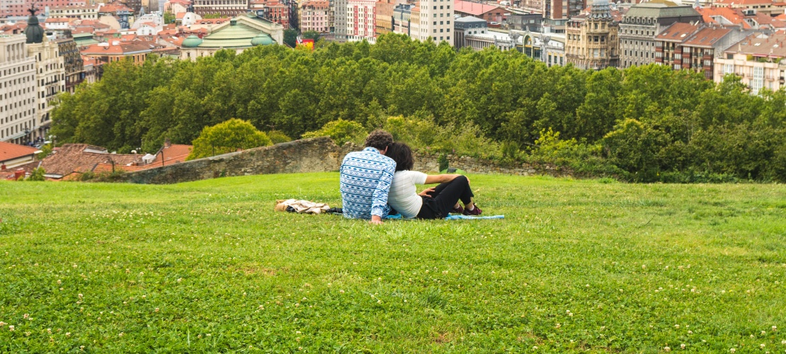 Un couple profite d'une magnifique vue panoramique sur Bilbao depuis un banc du parc de la colline qui surplombe la vieille ville